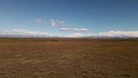 endless dry plains in sunshine with snow-capped mountains in the distance