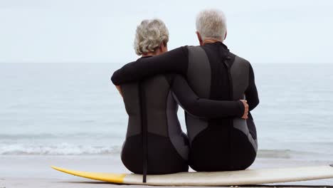 Mature-couple-sitting-on-surfboard