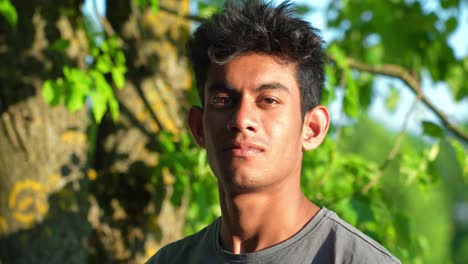 Slow-motion-of-brown-Asian-man-gazing-constantly-into-the-camera,-standing-outdoors