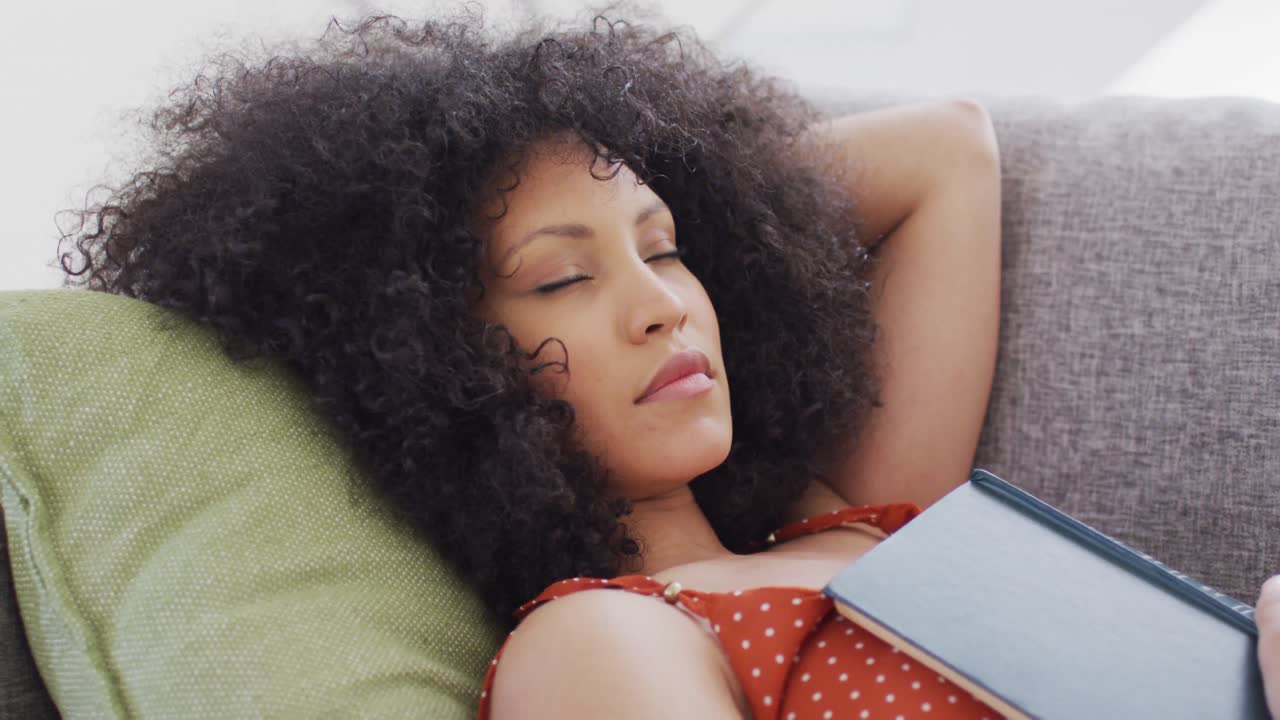 mujer con libro durmiendo en el sofá en casa