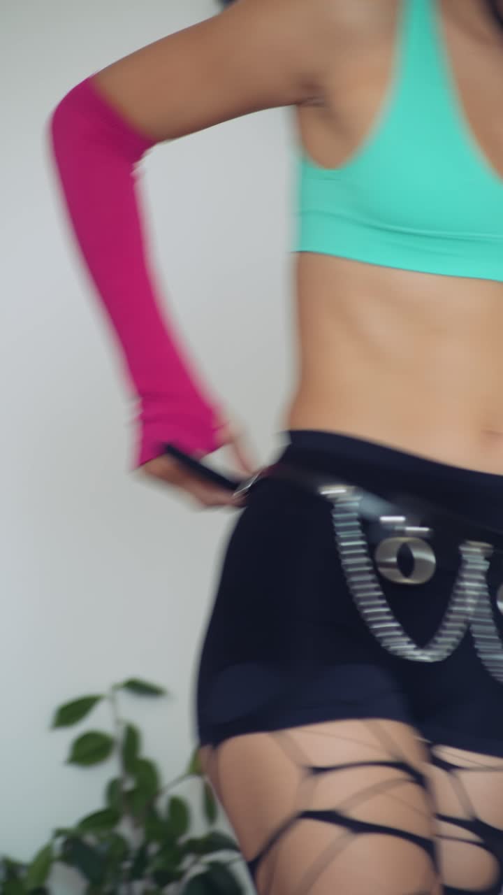Giovane donna con un look alternativo in posa e che balla all'interno