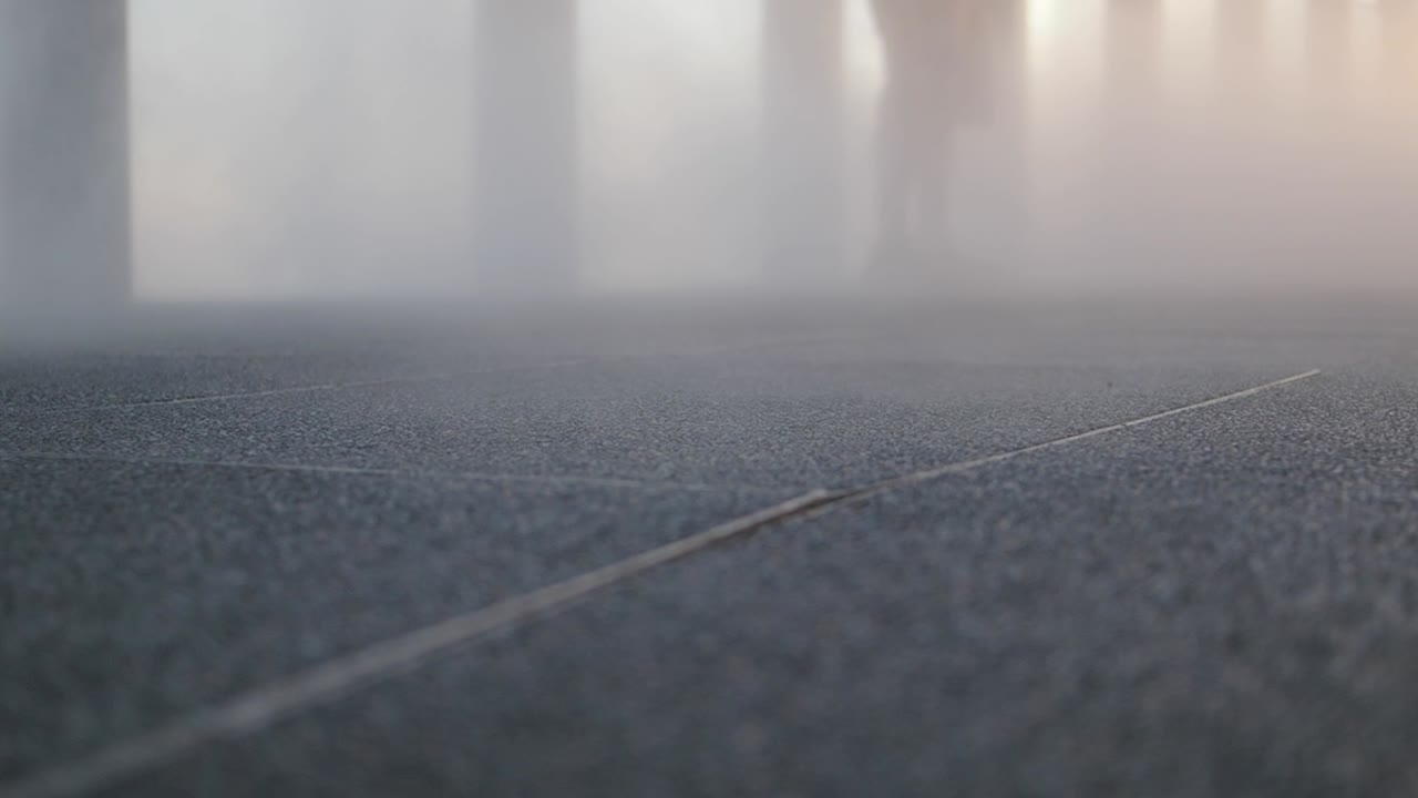 People Walking Through Thick Mist on Paved Ground
