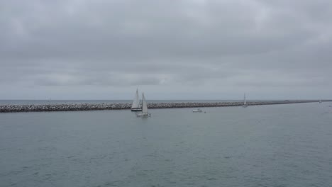 A-beautiful-aerial-drone-shot,-drone-flying-towards-and-circulating-sailboats,-Dana-Point---Orange-County---California