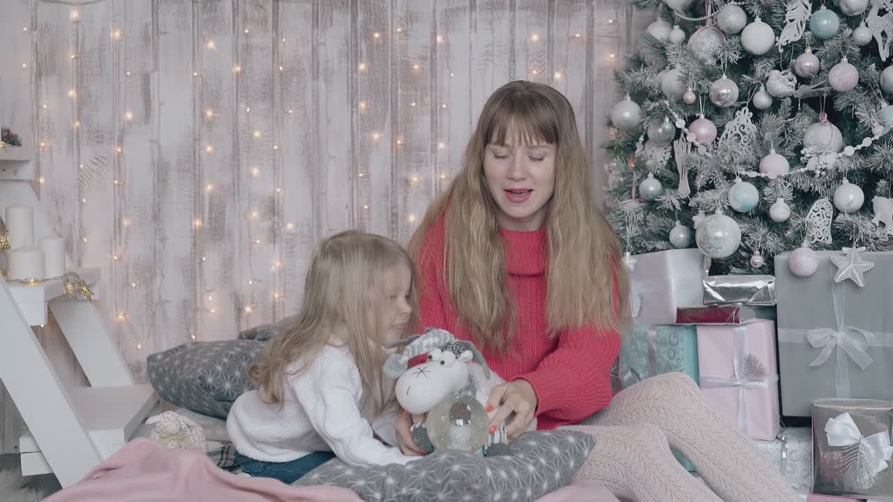 mamá se sienta en la cama con su hija y entretiene a la niña