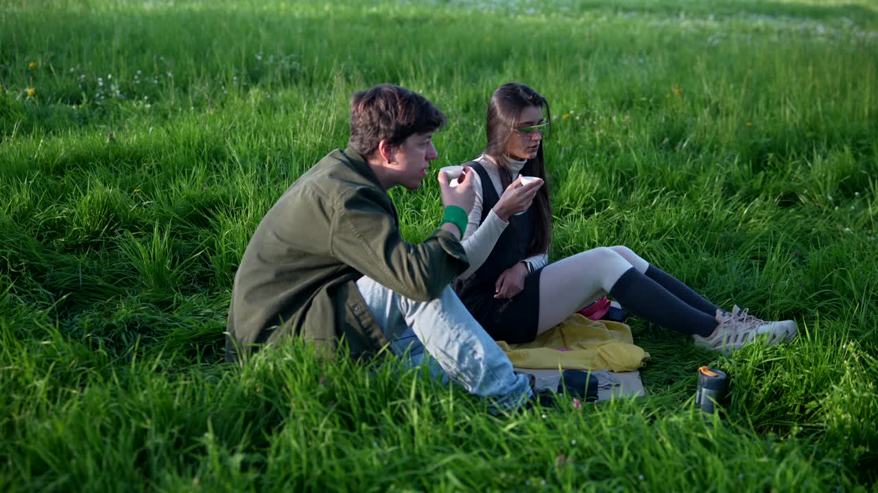 Couple enjoying a drink in a grassy park