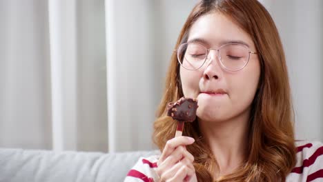 asian young woman in glasses tasting chocolate ice cream