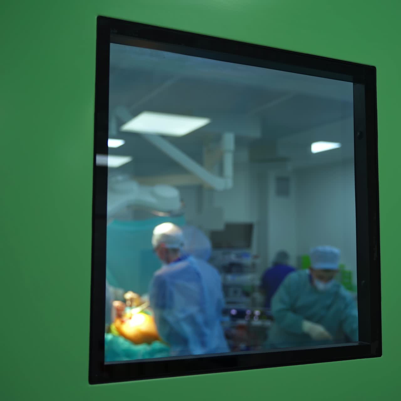 Surgery through the window. Operating procedure in surgical room. Window view on operation by a group of medical specialists.