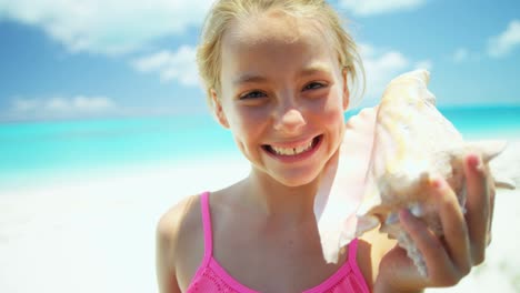portrait of girl on beach holding conch shell