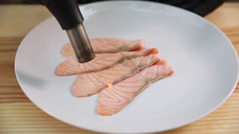 rebanadas de salmón asado con una antorcha culinaria