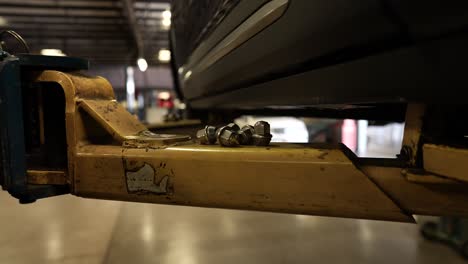 lug nuts on car lift, panning shot