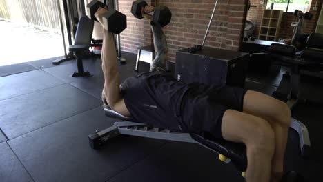 Tattooed-man-in-home-gym-doing-decline-chest-fly