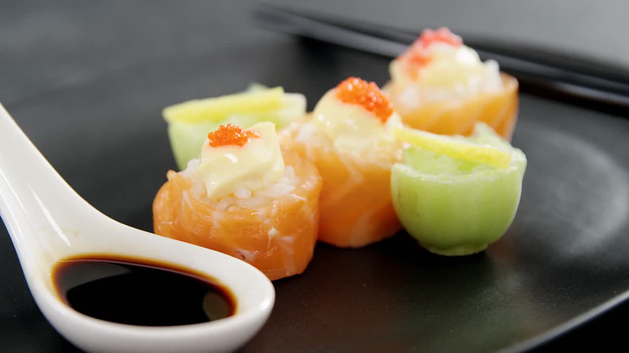 Sushi auf einem Teller mit Essstäbchen und Soße.