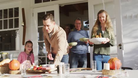 Video-Von-Glücklichen-Kaukasischen-Eltern,-Töchtern-Und-Großeltern,-Die-Essen-Für-Ein-Familienessen-Auf-Den-Tisch-Bringen