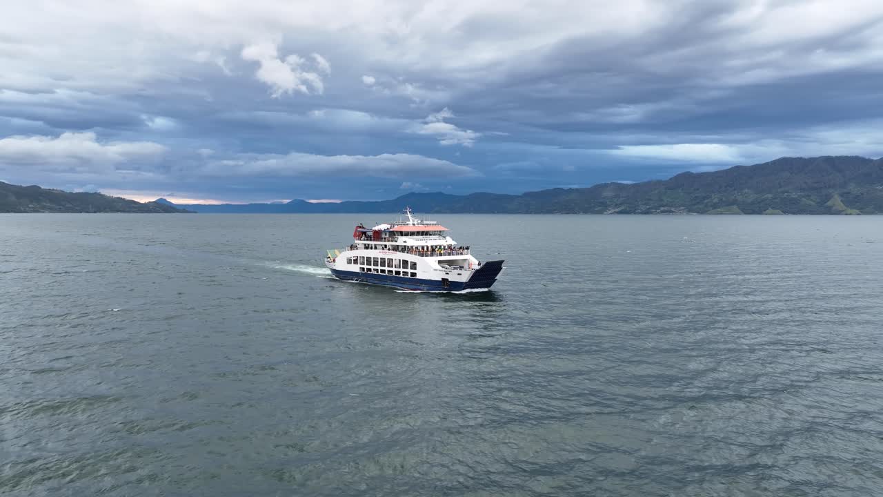 crucero en ferry por el lago toba bajo un cielo nublado, con el paisaje de sumatra como telón de fondo.