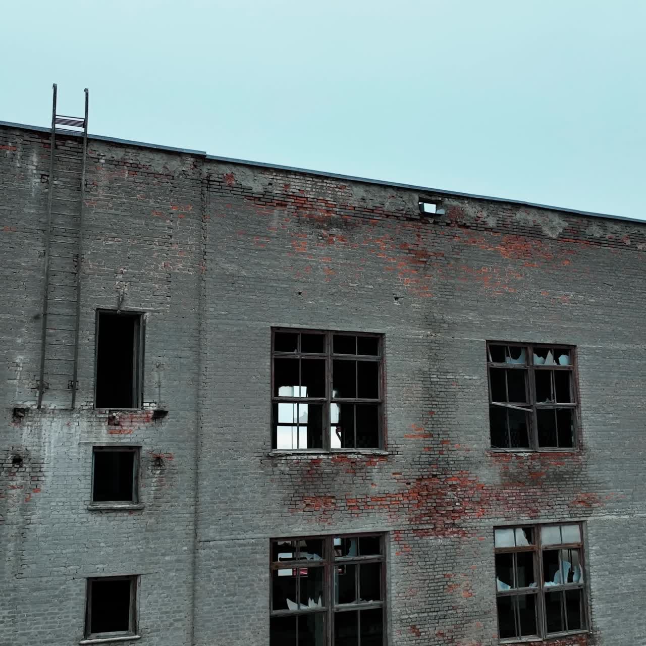Old brick factory building. Coming closer to the house with broken windows, empty inside. Blue sky backdrop