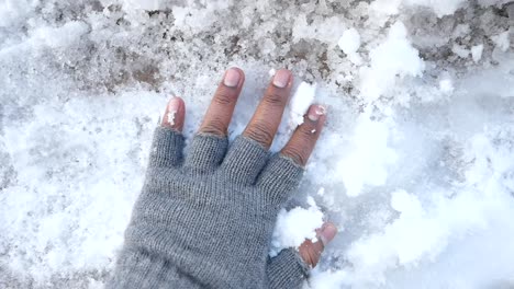 hand in gloves touching snow