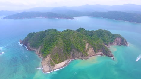 Aerial-view-of-an-island-of-the-coast-of-Costa-Rica-surrounded-by-magical-turquoise-blue-water-on-a-sunny-day-in-paradi