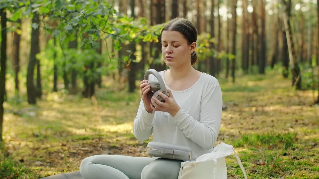 Woman Meditating with Headphones in the Forest