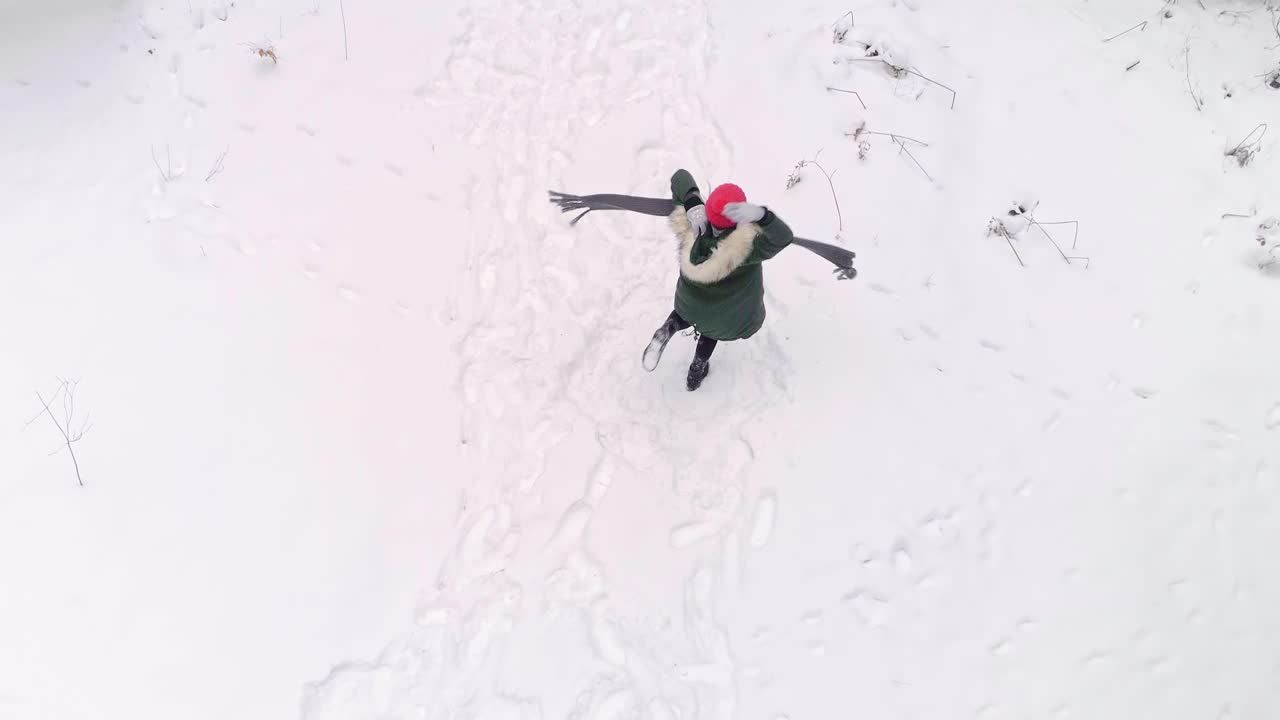 vista aérea de una mujer feliz bailando en el bosque de invierno