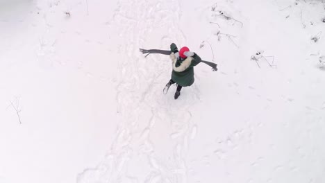 Vista-Aérea-De-Una-Mujer-Feliz-Bailando-En-El-Bosque-De-Invierno