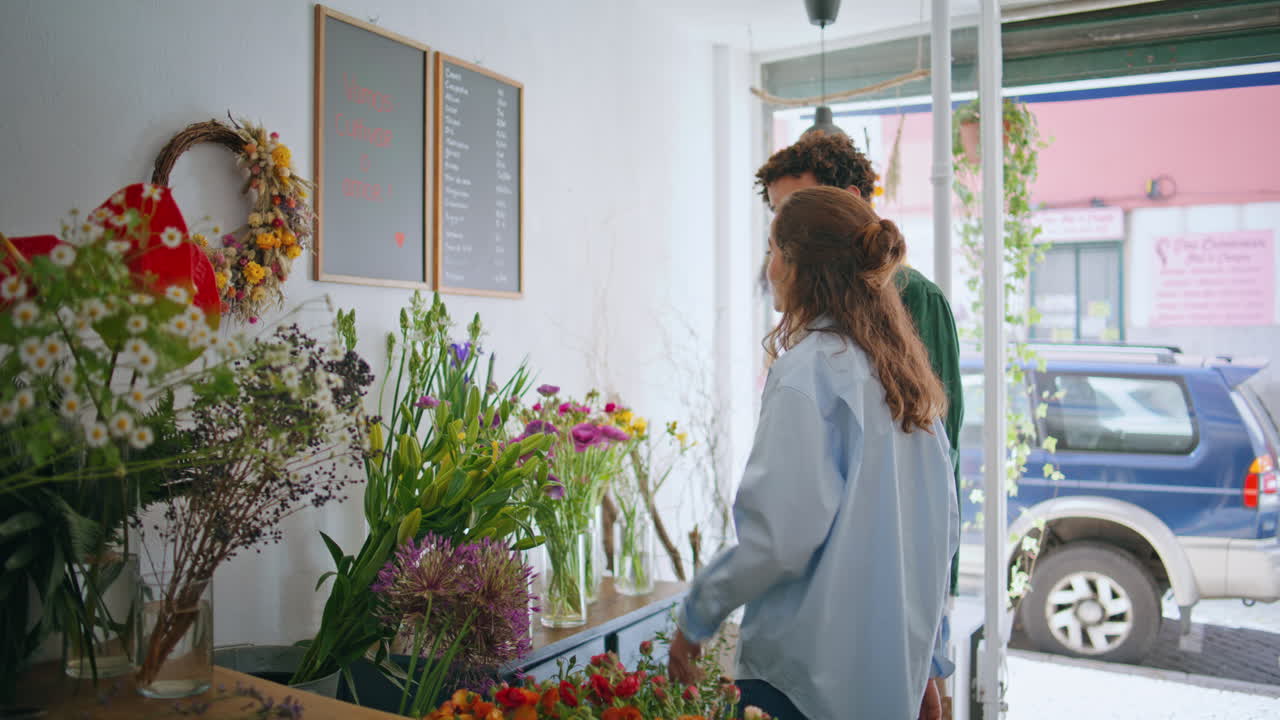 una pareja multiétnica disfruta juntos de la tienda de flores. dos amantes venden plantas de flores.