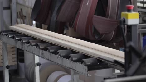 slow motion close-up of wood on a conveyor belt coming off a wood working machine