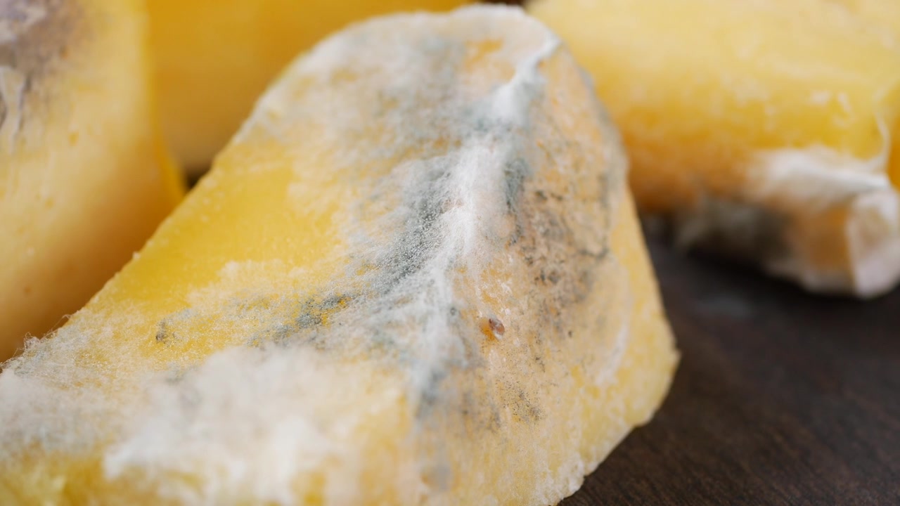 Primo piano di pezzi di formaggio ammuffito su una superficie di legno.