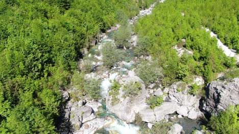 Drohnenansicht-In-Albanien-In-Den-Alpen,-Die-über-Einen-Fluss-Mit-Grünem-Und-Blauem-Wasser-In-Einem-Grünen-Tal-In-Theth-Fliegt