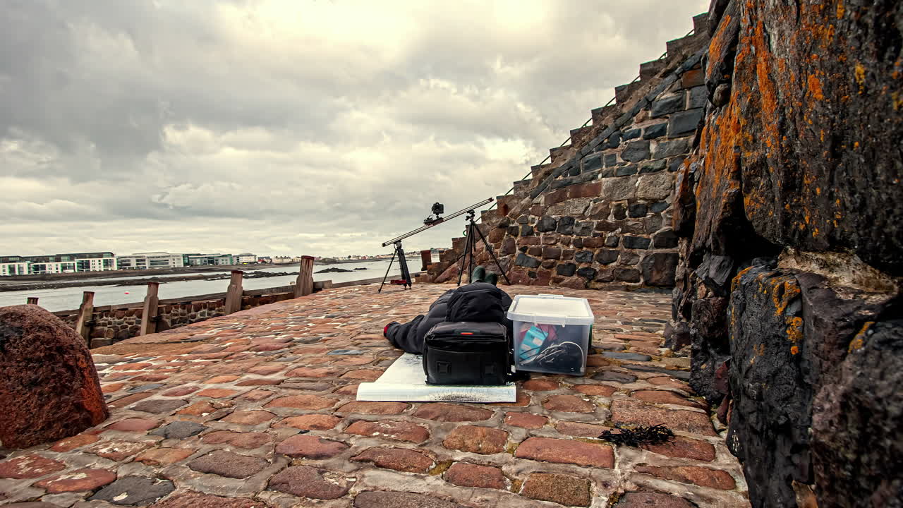 Time lapse di un creatore di contenuti che attende il completamento di una configurazione motion time lapse su slider - nuvole che volano nel cielo a Guernsey