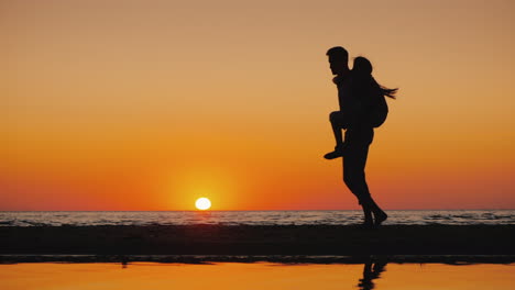 A-Young-Man-Plays-With-A-Child-Carries-Him-On-His-Shoulders-On-The-Beach