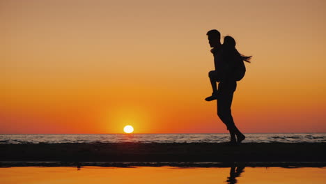 a young man plays with a child carries him on his shoulders on the beach