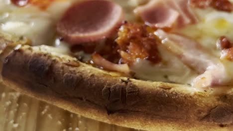 close up shot of pizza crust with ham and cheese, handheld