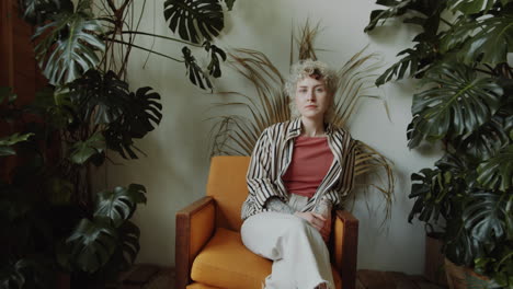 Young-Girl-Sitting-in-Room-with-Plants-and-Posing-for-Camera