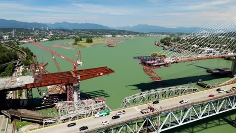 the pattullo bridge replacement is currently being built over the fraser river in vancouver, british columbia, canada - aerial drone shot