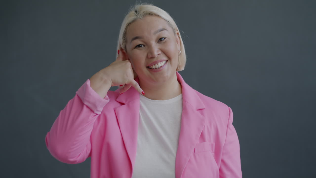 Kvinde i pink blazer laver en telefongestus