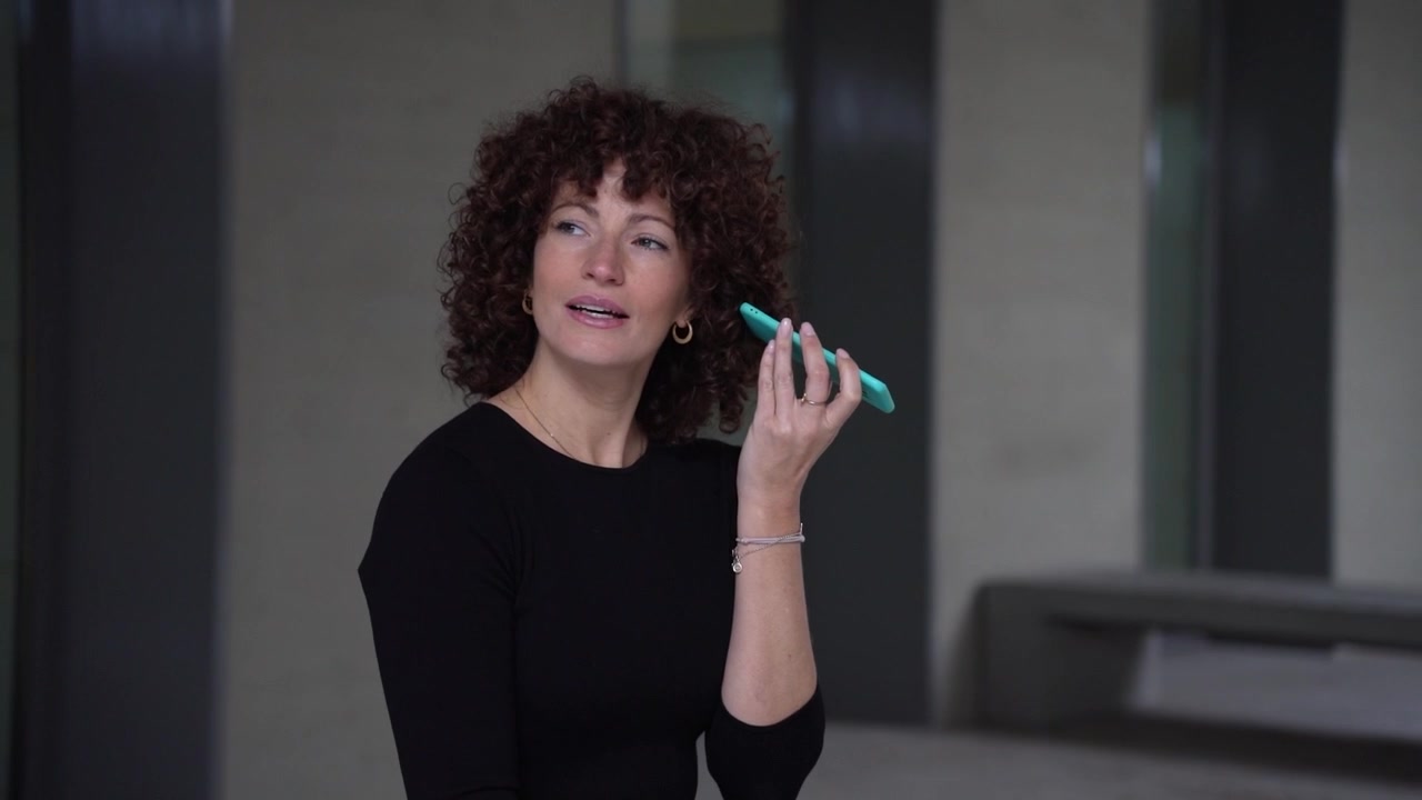 A joyful woman happily engaging with her smartphone in a modern interior space around her
