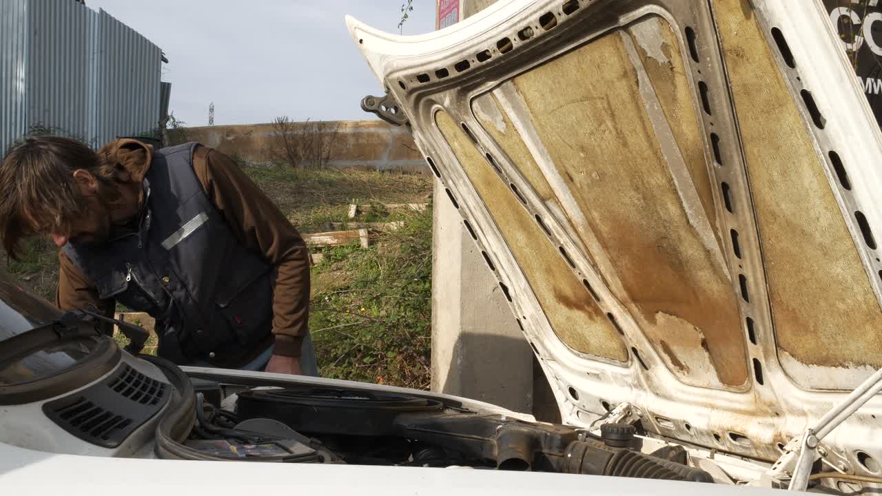 Mechanic man checks air filter box of vintage car with forward opening hood
