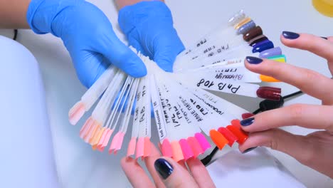 nail technician shows the color palette of nail services in beauty salon.