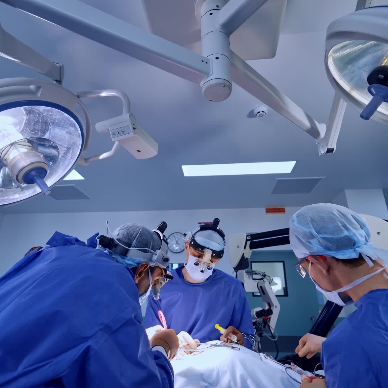 Neurosurgical operation in modern clinics. Two surgeons and assistant are busy at operation. Advanced medical equipment at backdrop