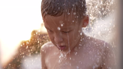 Junge-Nimmt-Stranddusche-Bei-Sonnenuntergang