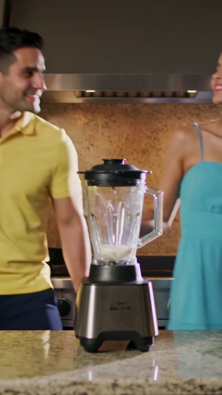 Vertical video: Starting man pressing blender, couple preparing drink in kitchen in yellow and teal