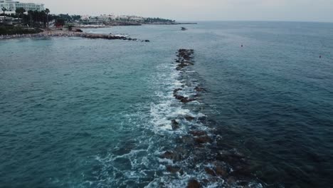 Toma-Aérea-De-Drones-De-Olas-Rompiendo-Sobre-Rocas-En-El-Mar---Paphos,-Chipre