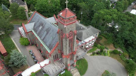 an aerial view of a large church in a suburban neighborhood on long island, ny with green trees on a cloudy day