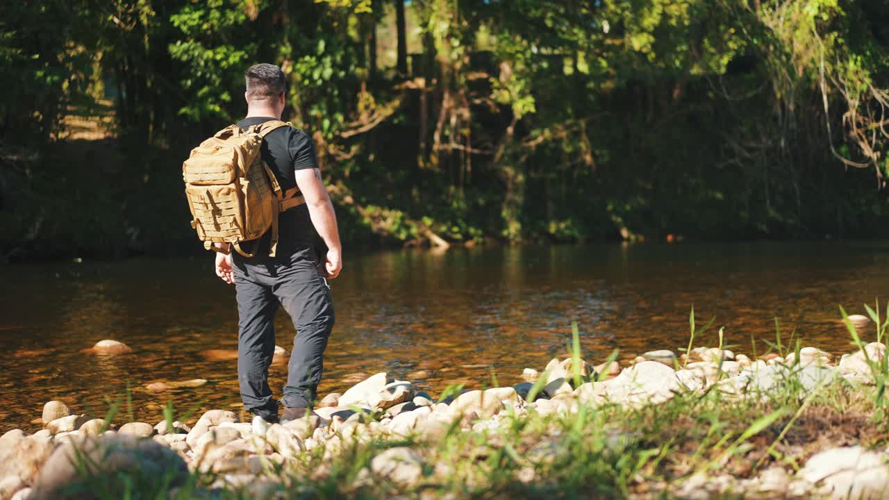 Male hiker standing near a river surounded by jungle