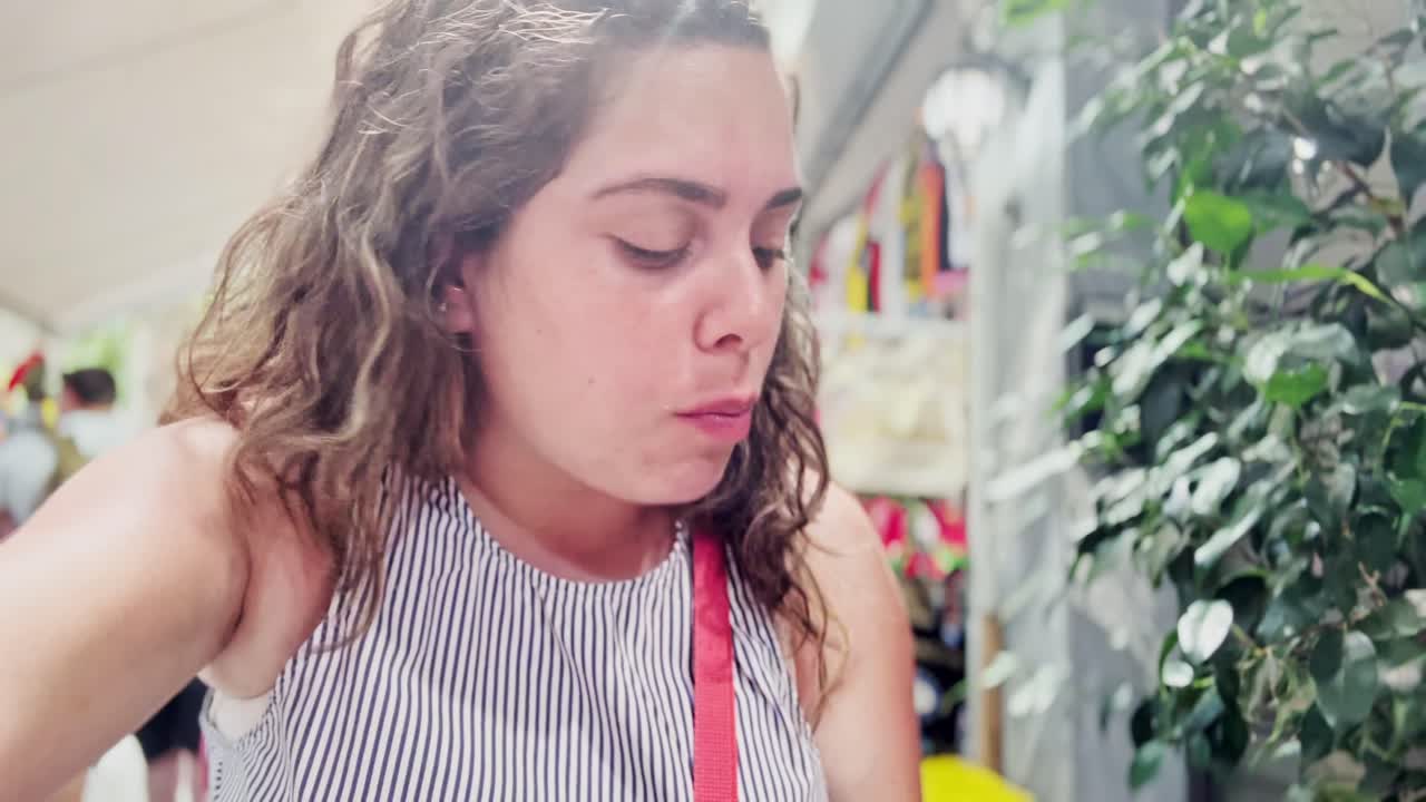 A young woman enthusiastically eats a delicious souvlaki,