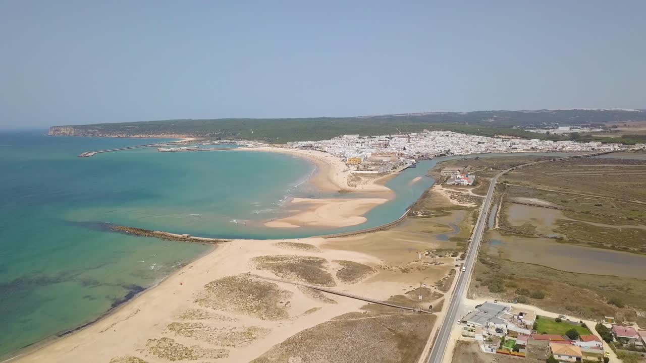 toma aerea de la playa de barbate con el pueblo blanco y la colina detras en españa
