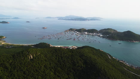 aerial view of binh hung island with many anchored boats in bay with epic mountain landscape and ocean in vietnam