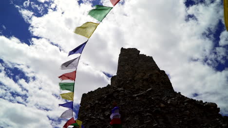 tibetan prayer flags in the wind at buddhist monastery ruins in the himalayas, camera pointing up