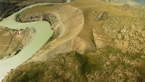 meandering river in hilly valley fpv drone. mountain entrenched stream course hidden between sloppy banks at highland area. watercourse observing