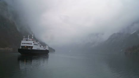 a ferry boat sails through mysterious fog on a fjord in norway